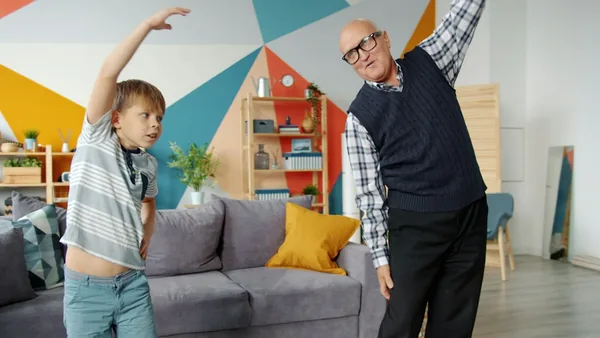 Stock photo of a grandfather and grandson stretching in a living room